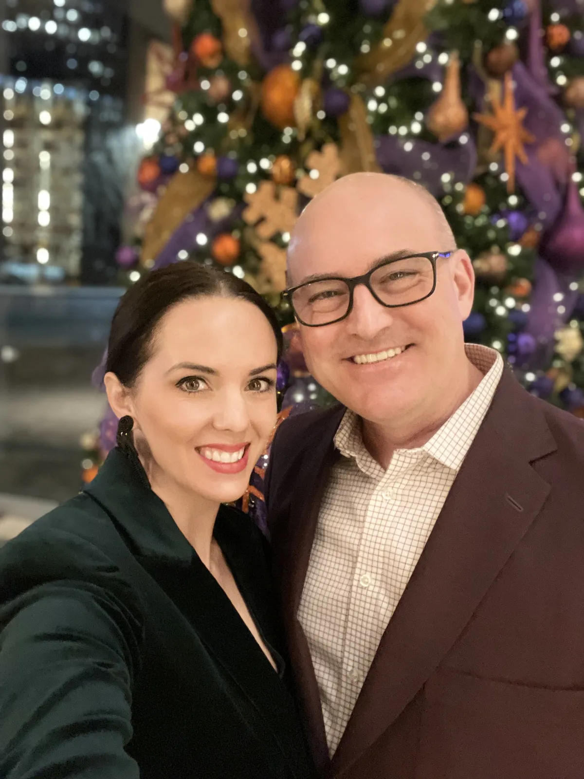 Jason and Heather in front of a giant purple and gold lit Christmas tree in Atlanta