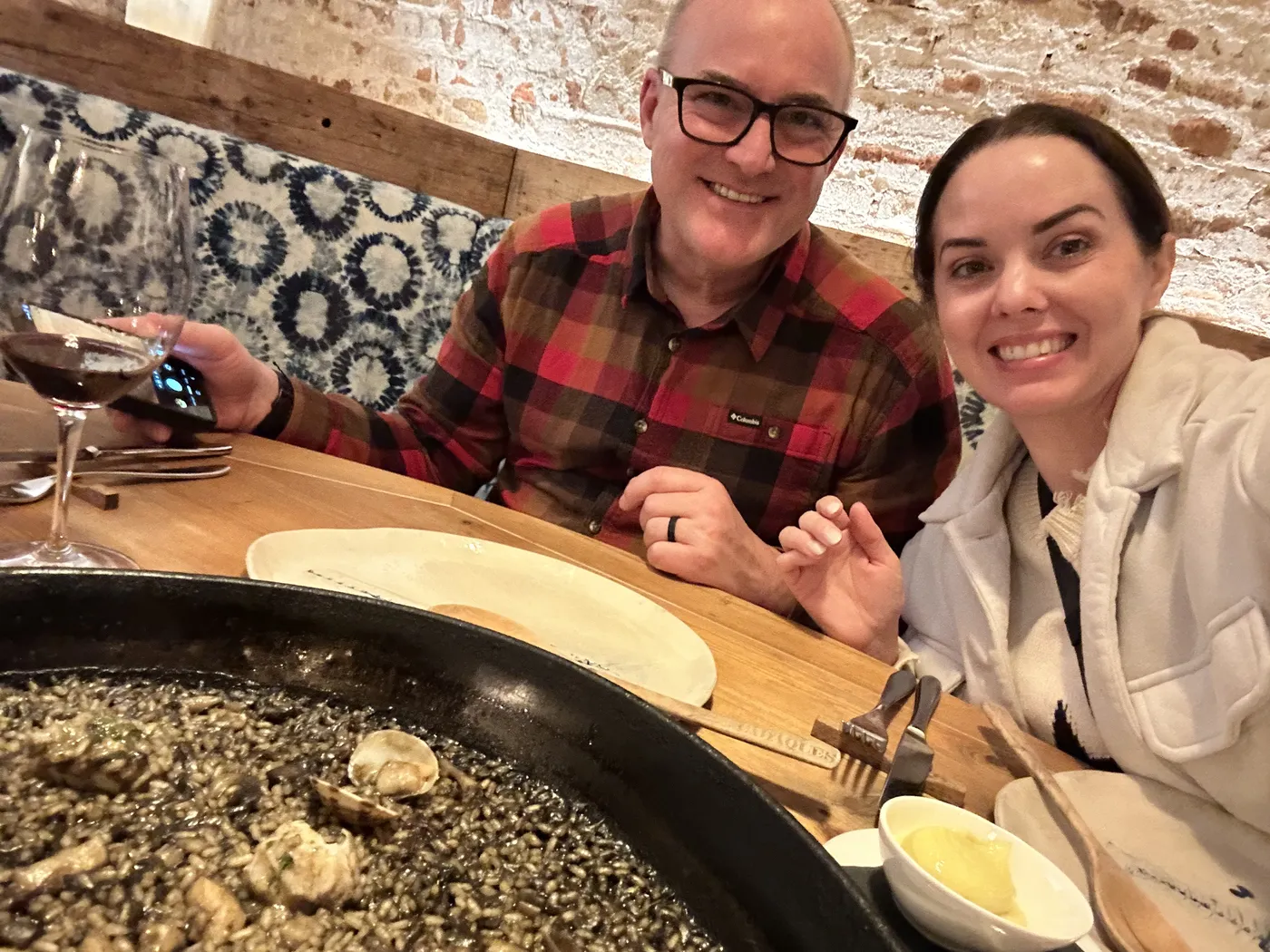 Jason and Heather at dinner with Spanish wine and a pan of black rice in Barcelona