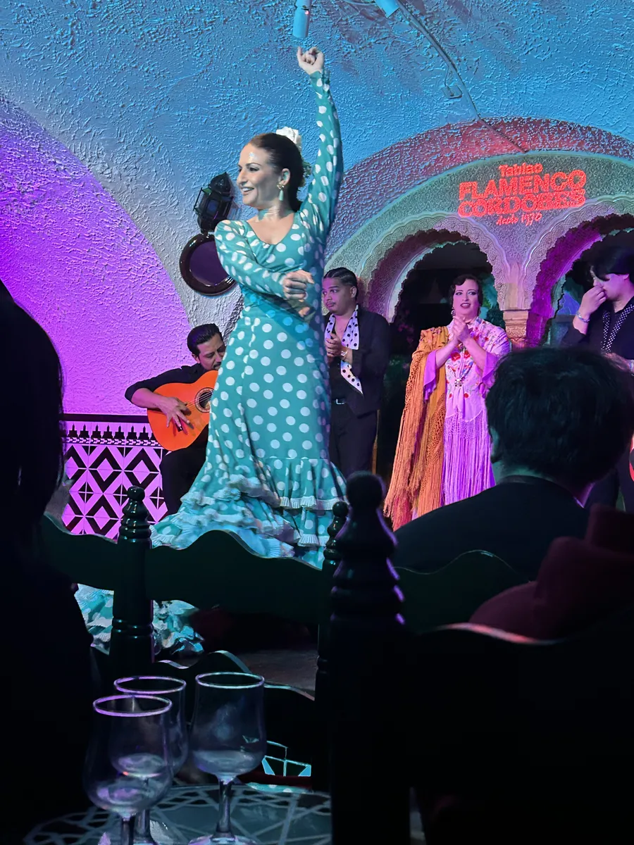 Flamenco dancer with a fan performing with guitarists and singers