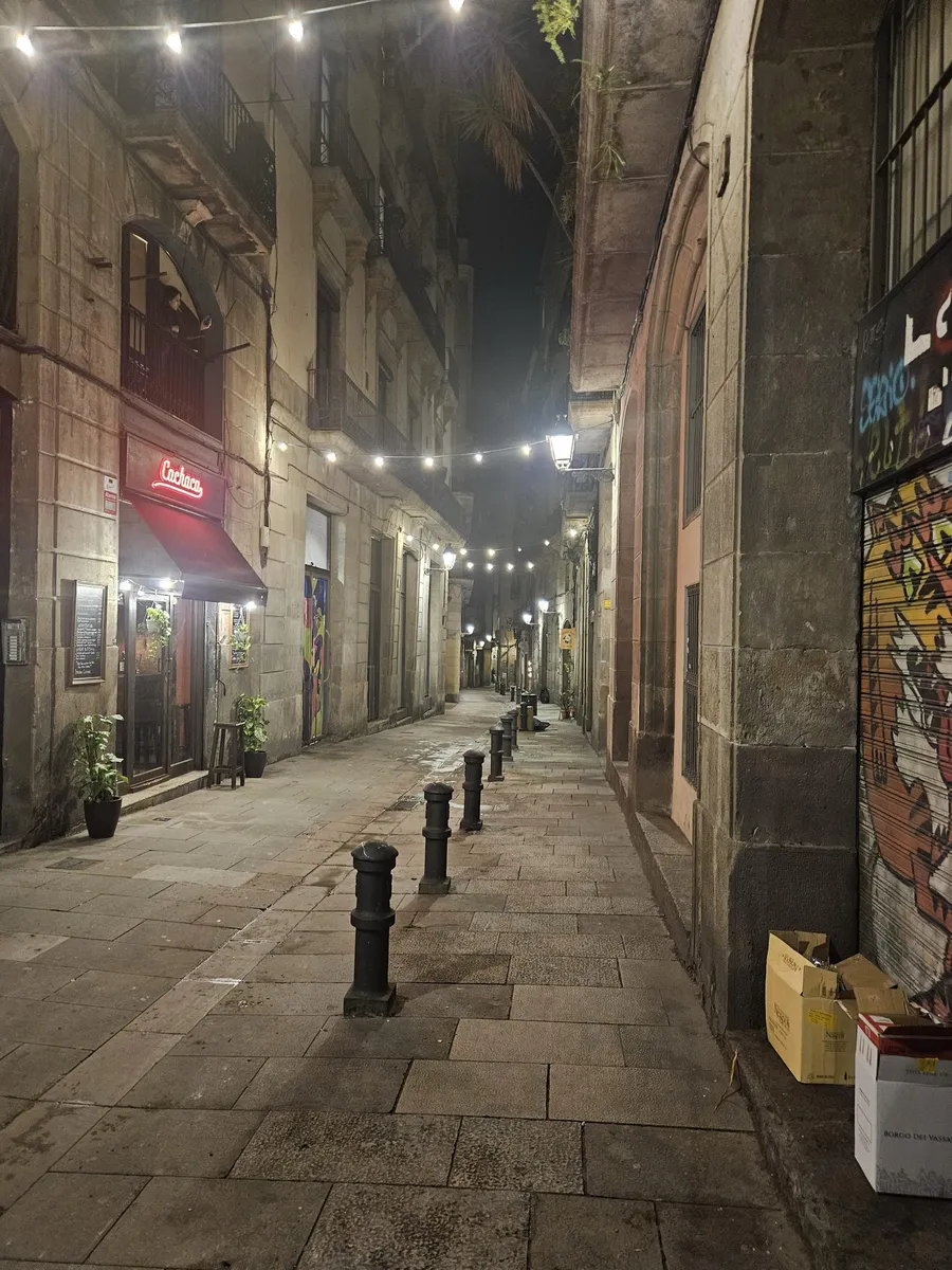 Narrow Gothic Quarter street at night with string lights overhead