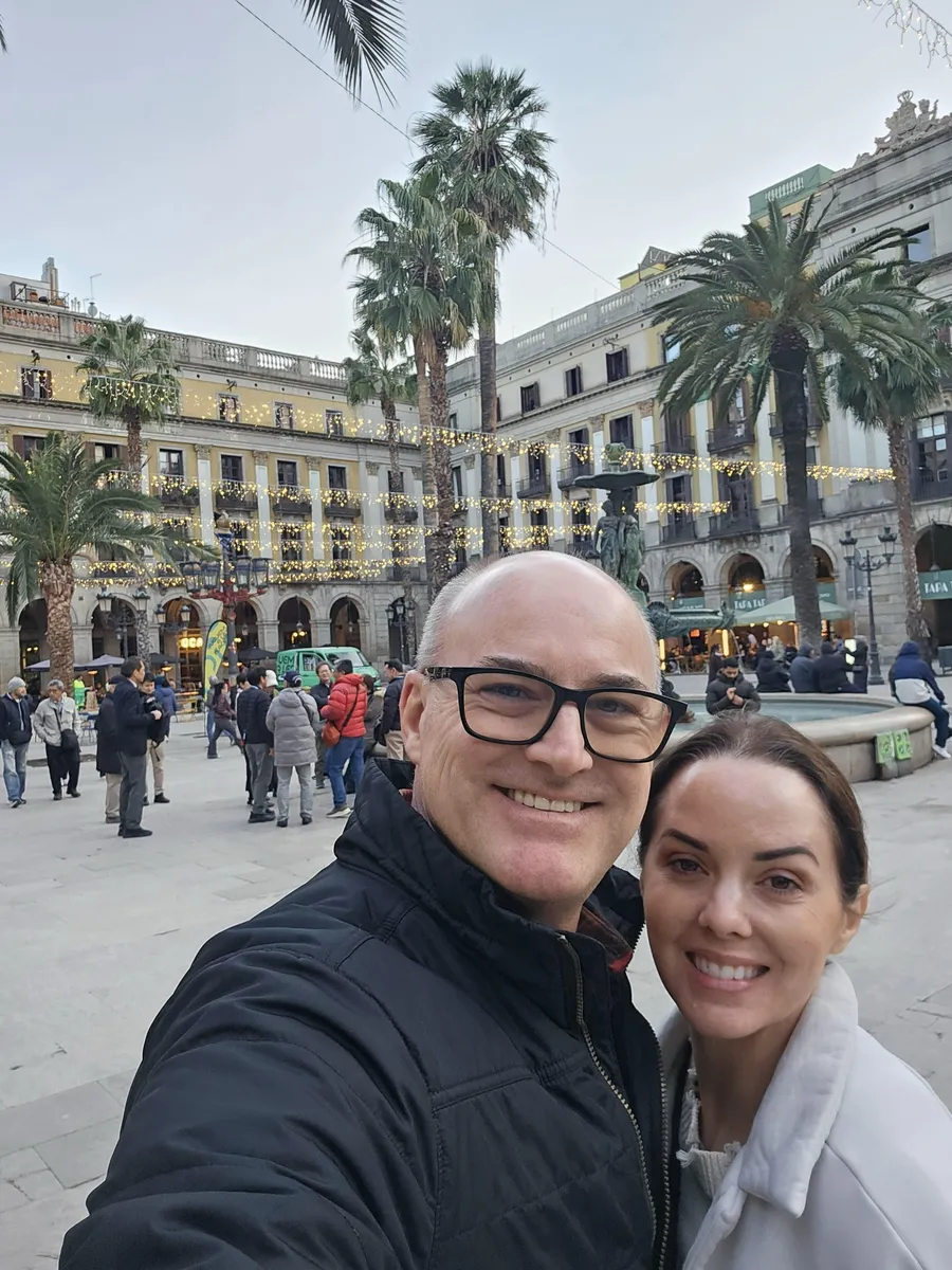 Jason and Heather in Plaça Reial with palm trees and the fountain behind them