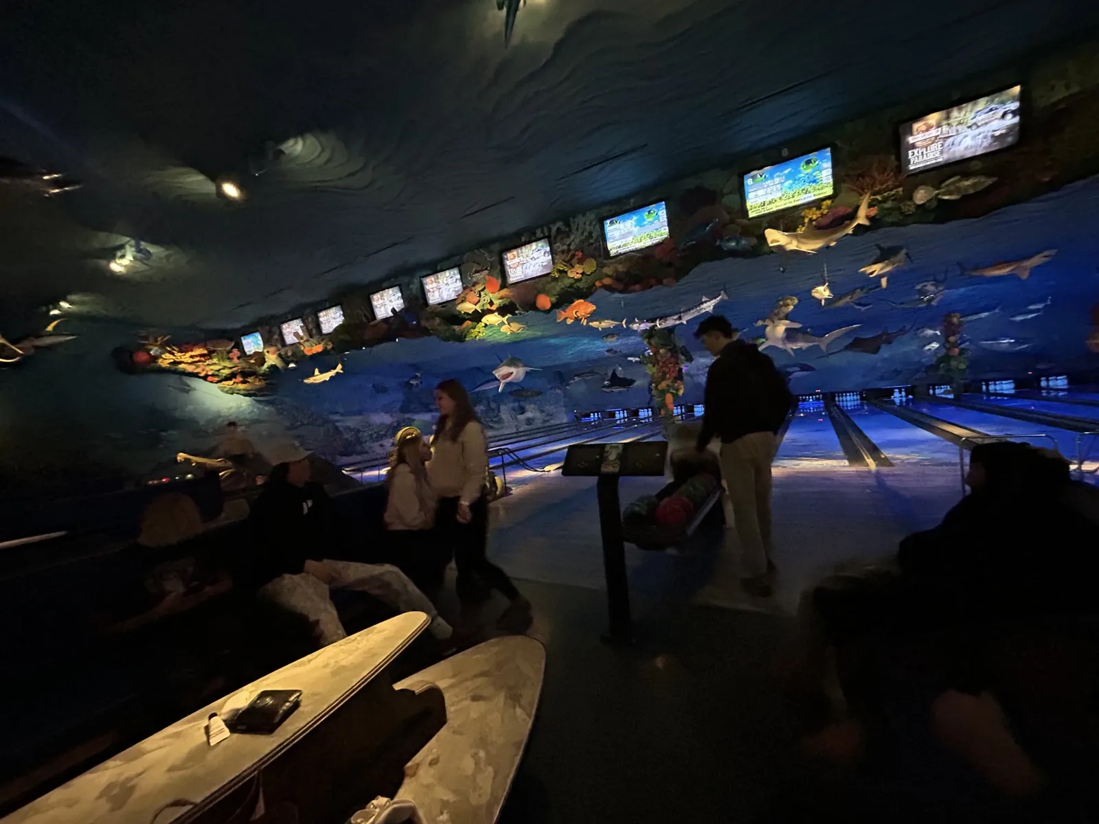 Underwater-themed bowling alley glowing blue with sea creatures hanging over the lanes