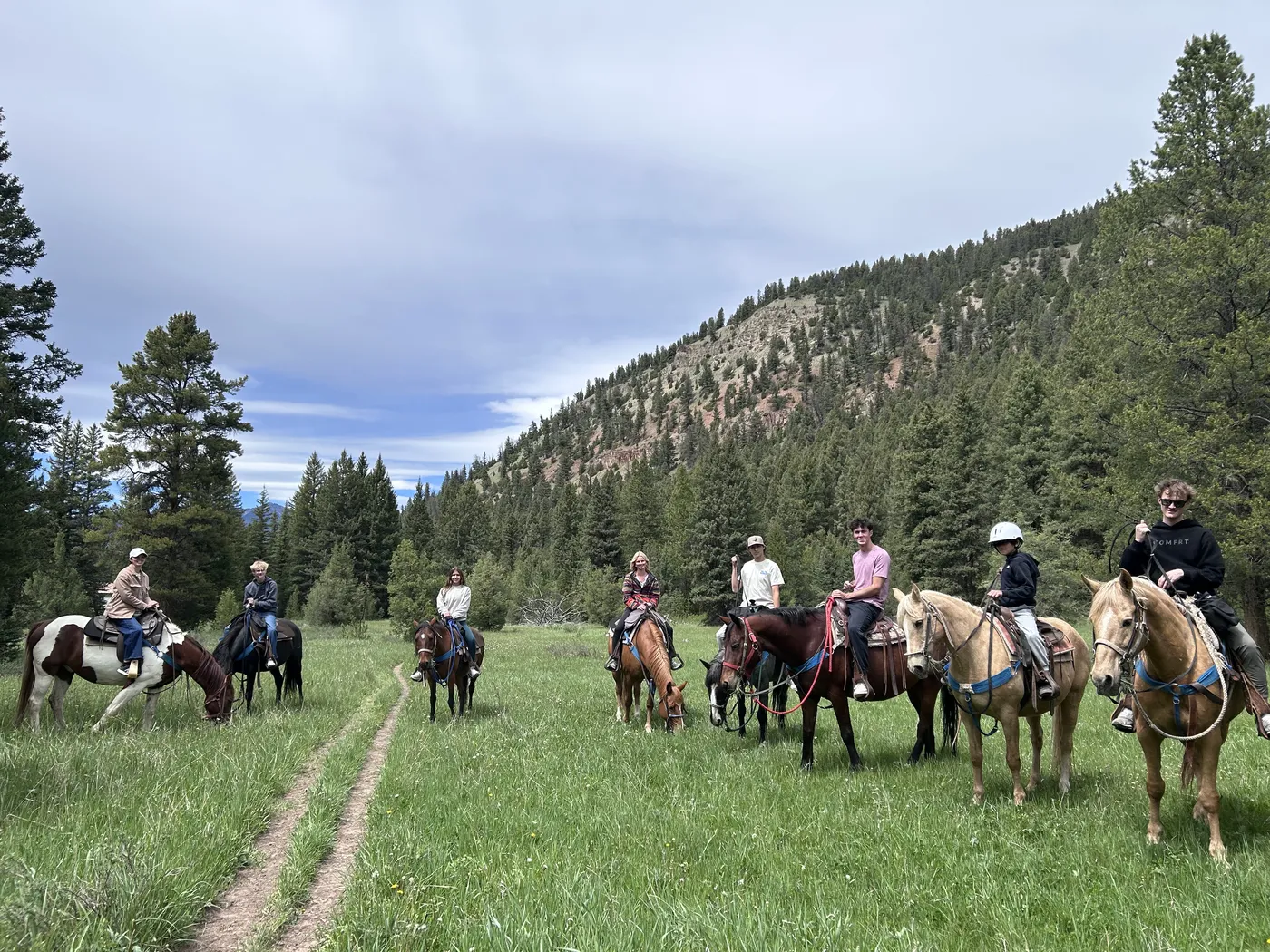 Family on a horseback trail ride in a mountain meadow near Big Sky, Montana