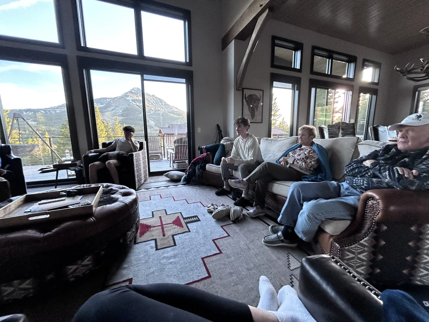 Family relaxing in the living room of a Big Sky rental house with mountain views