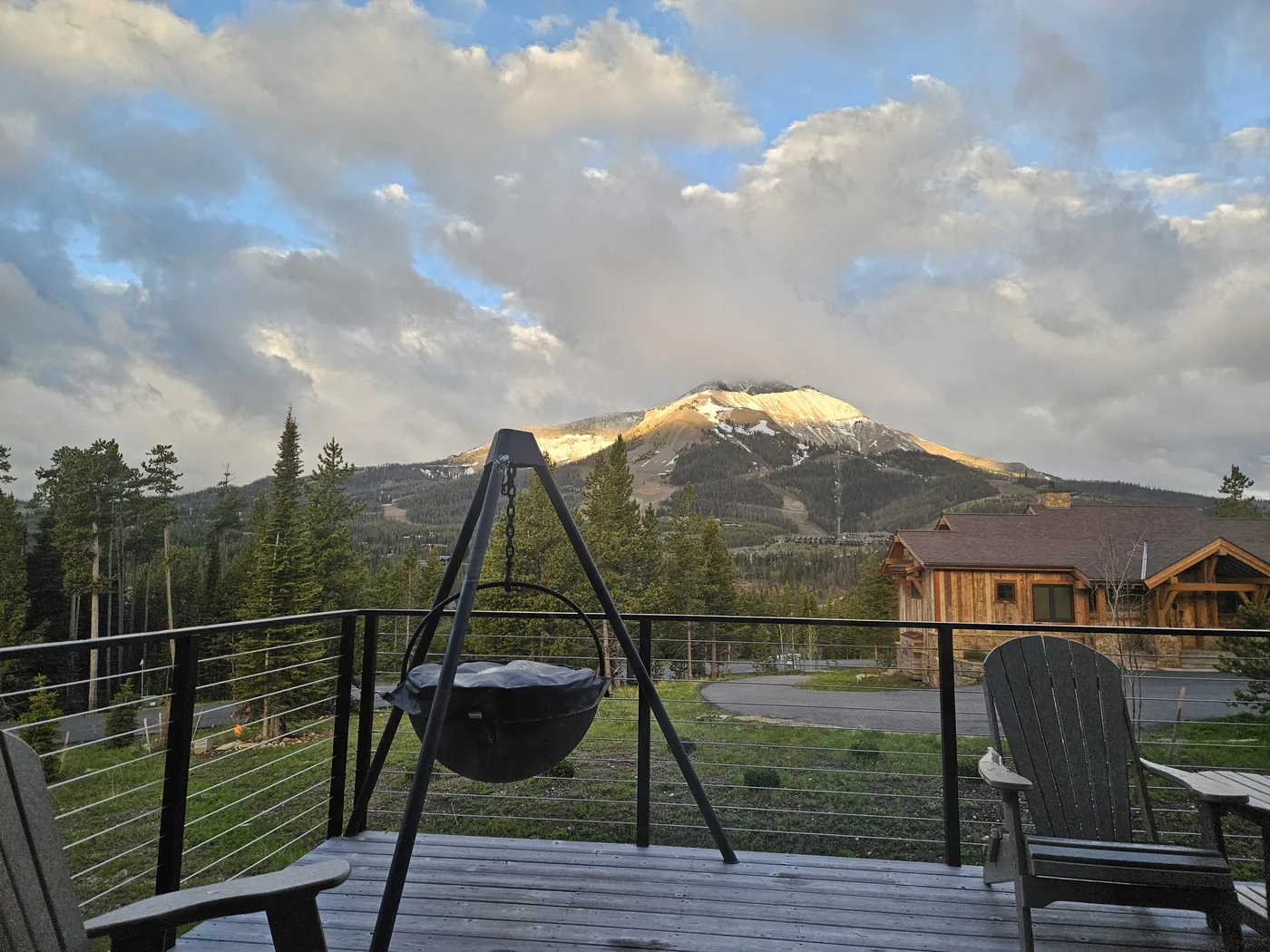 Lone Peak lit by early morning sun under clouds, seen from a rental house deck in Big Sky, Montana