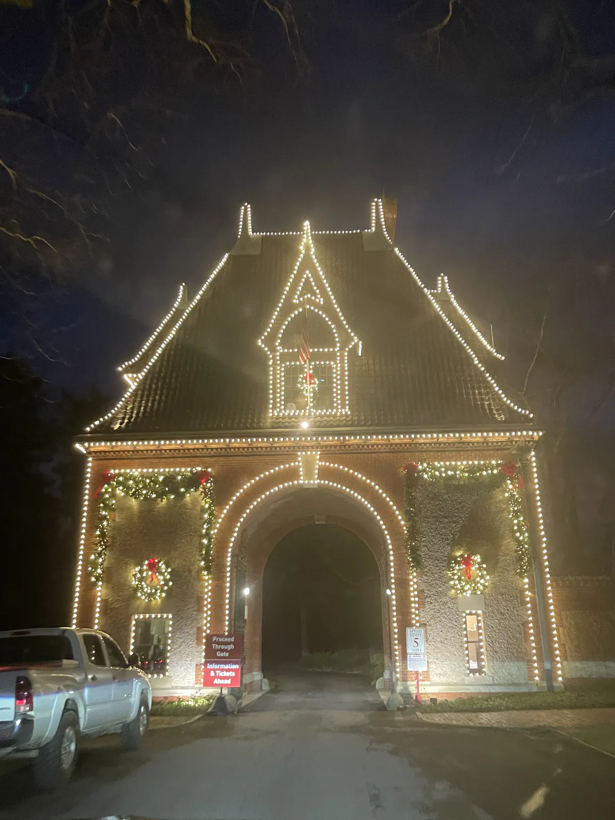 Biltmore's stone gatehouse outlined in white Christmas lights at night