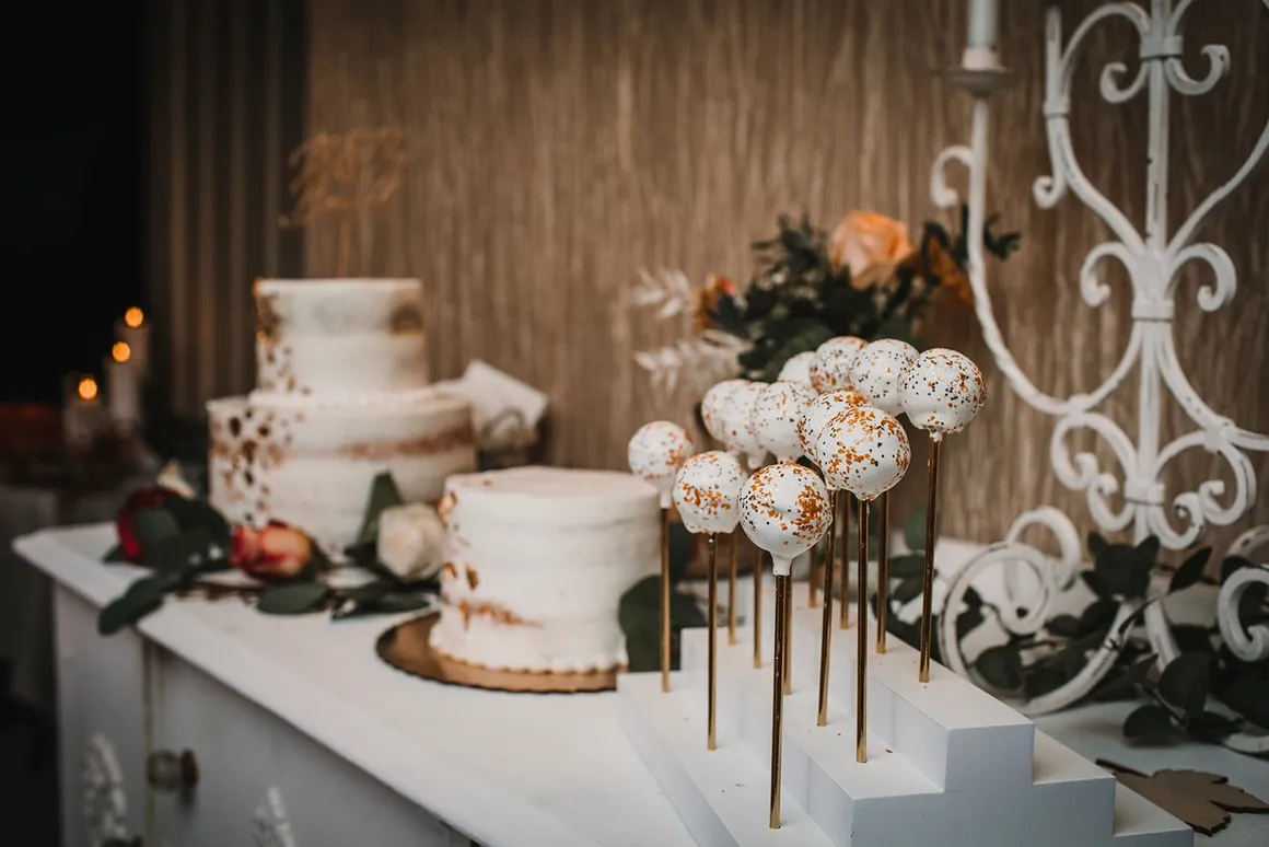Cake table with white wedding cake, cake pops, and the chalk-painted white dresser