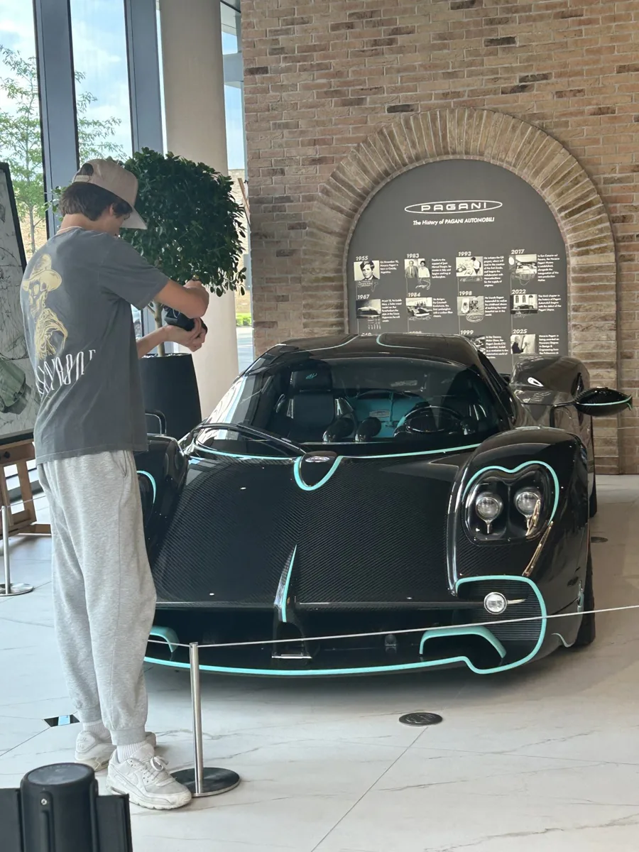 A teen filming a carbon fiber Pagani with teal accents
