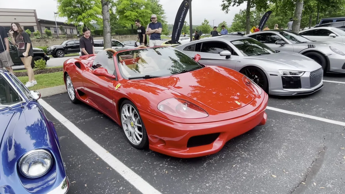 A red Ferrari 360 Spider parked next to an Audi R8 at a car meet