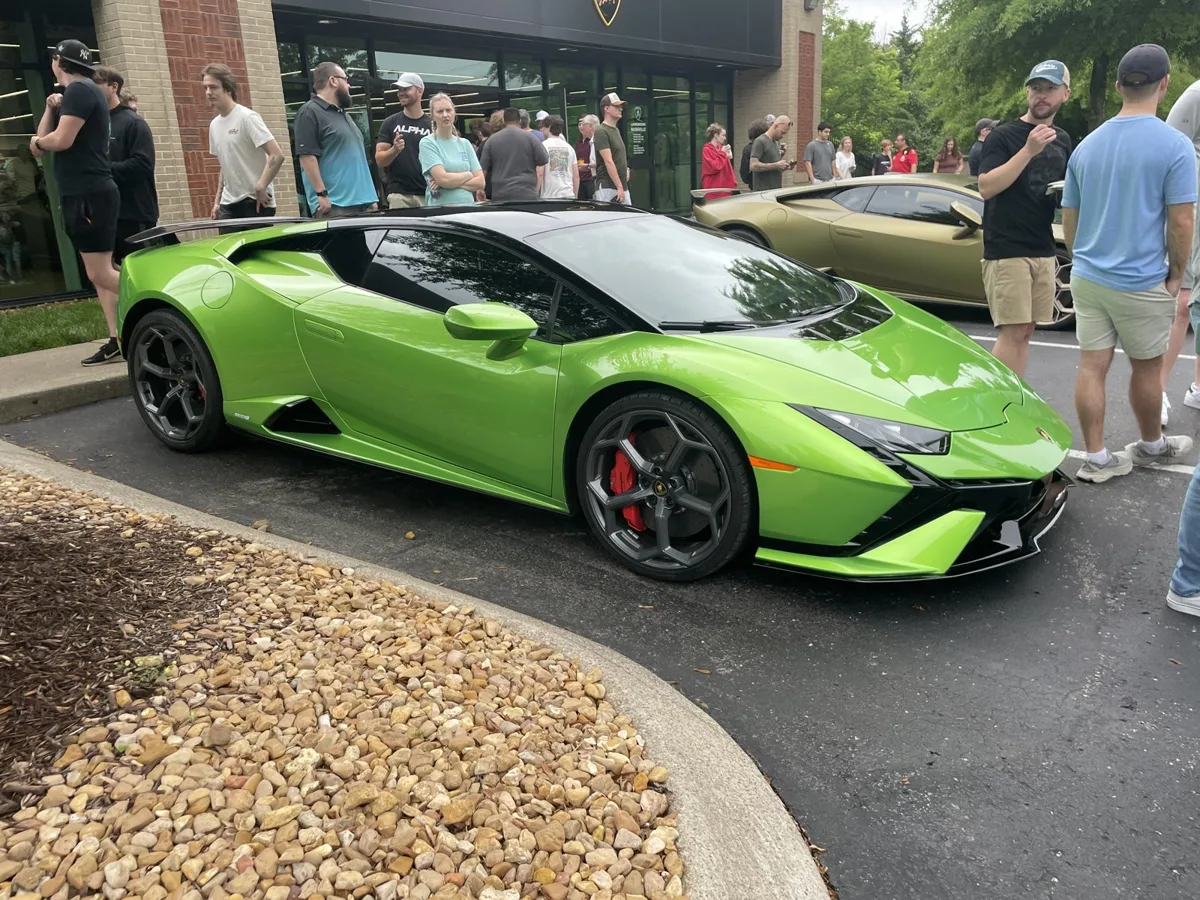 A green Lamborghini Huracán Tecnica drawing a crowd at a car meet