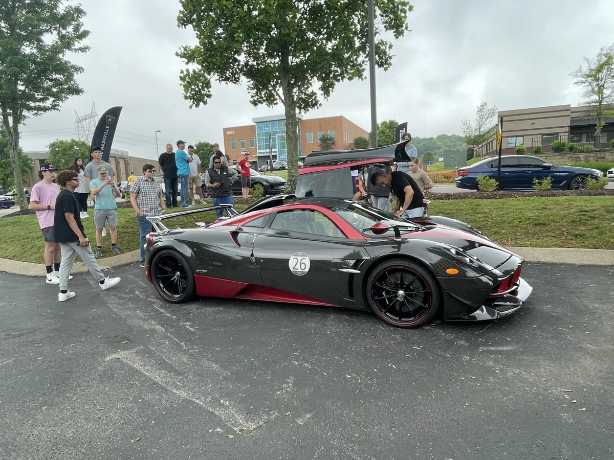 A black and red Pagani Huayra surrounded by onlookers at a cars and coffee meet