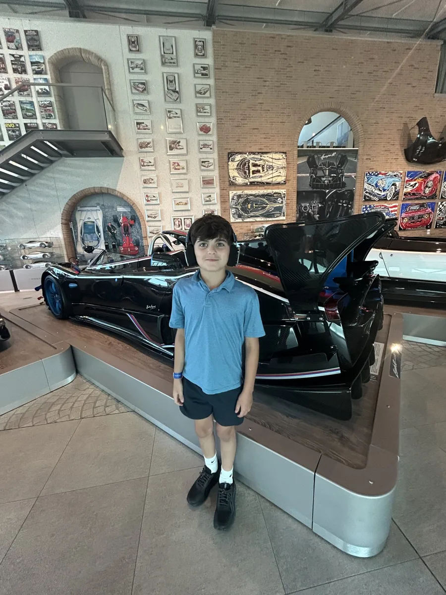 A boy standing in front of a Pagani hypercar on display in Italy