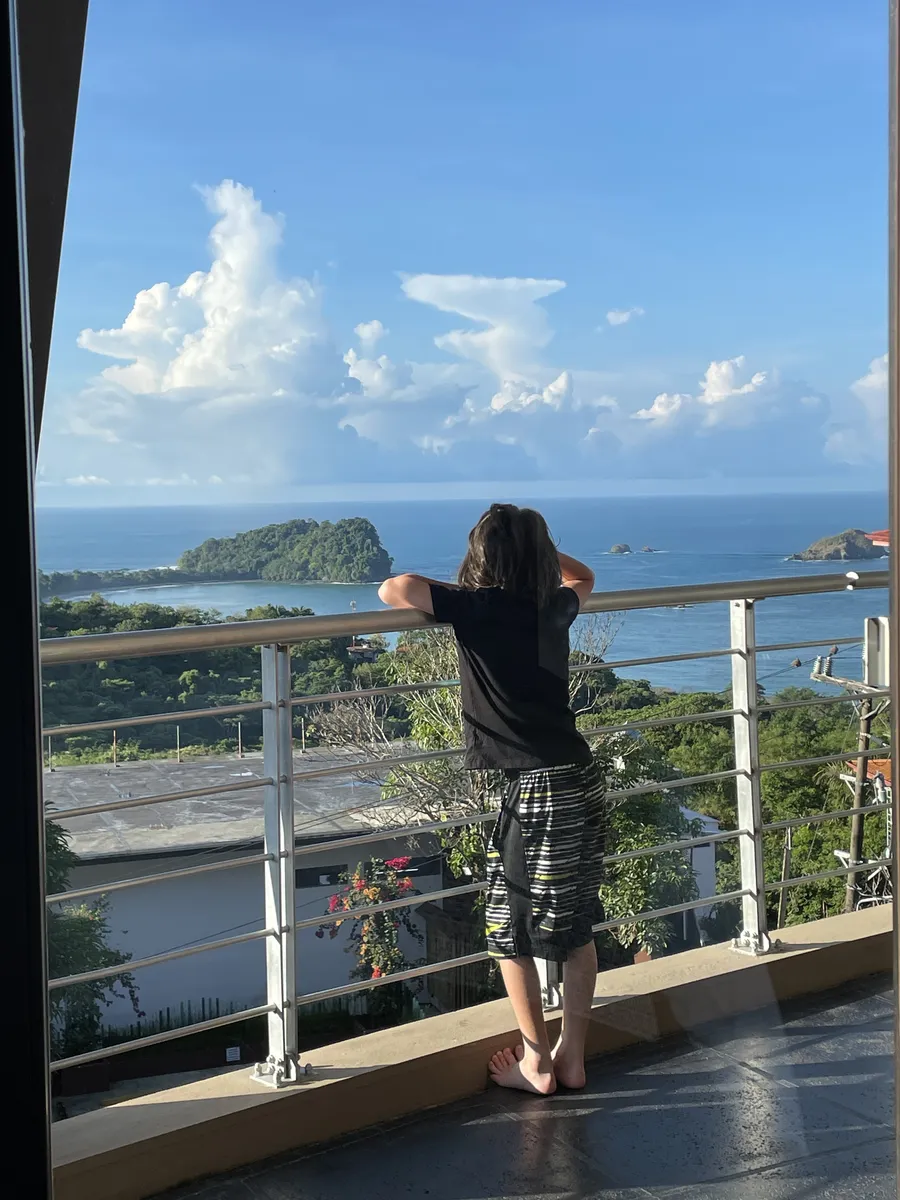 Teen looking out from a Los Altos balcony over the ocean in Manuel Antonio