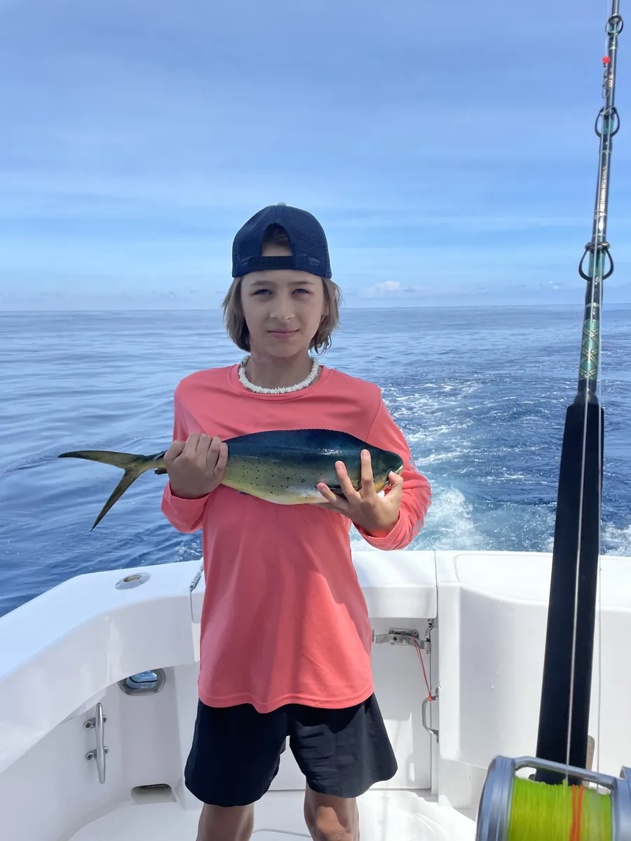 Boy holding a mahi-mahi on a fishing boat off Costa Rica
