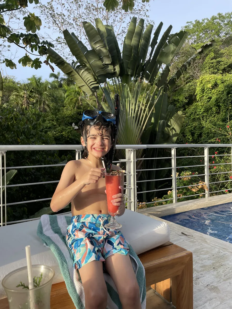 Boy relaxing by the pool with a drink in Manuel Antonio