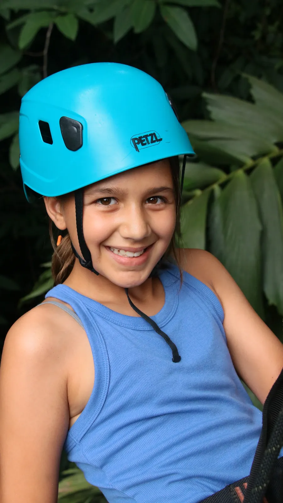 Girl in a blue helmet smiling on a zipline platform