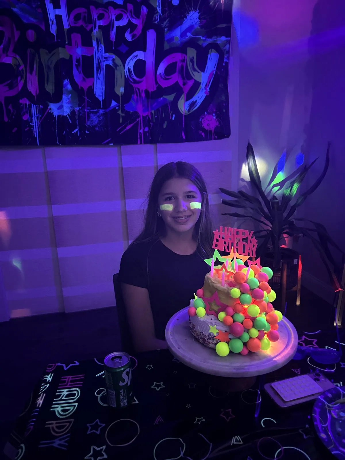 Birthday girl with a glowing neon cake at an at-home glow party