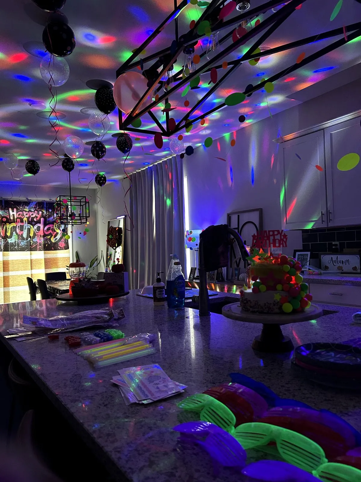 Kitchen island set with LED glasses, glow sticks and a neon cake under disco lights