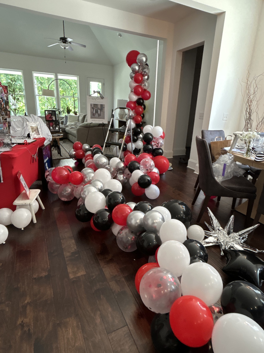 Red, black, white, silver and confetti balloons assembled into a garland on the living room floor