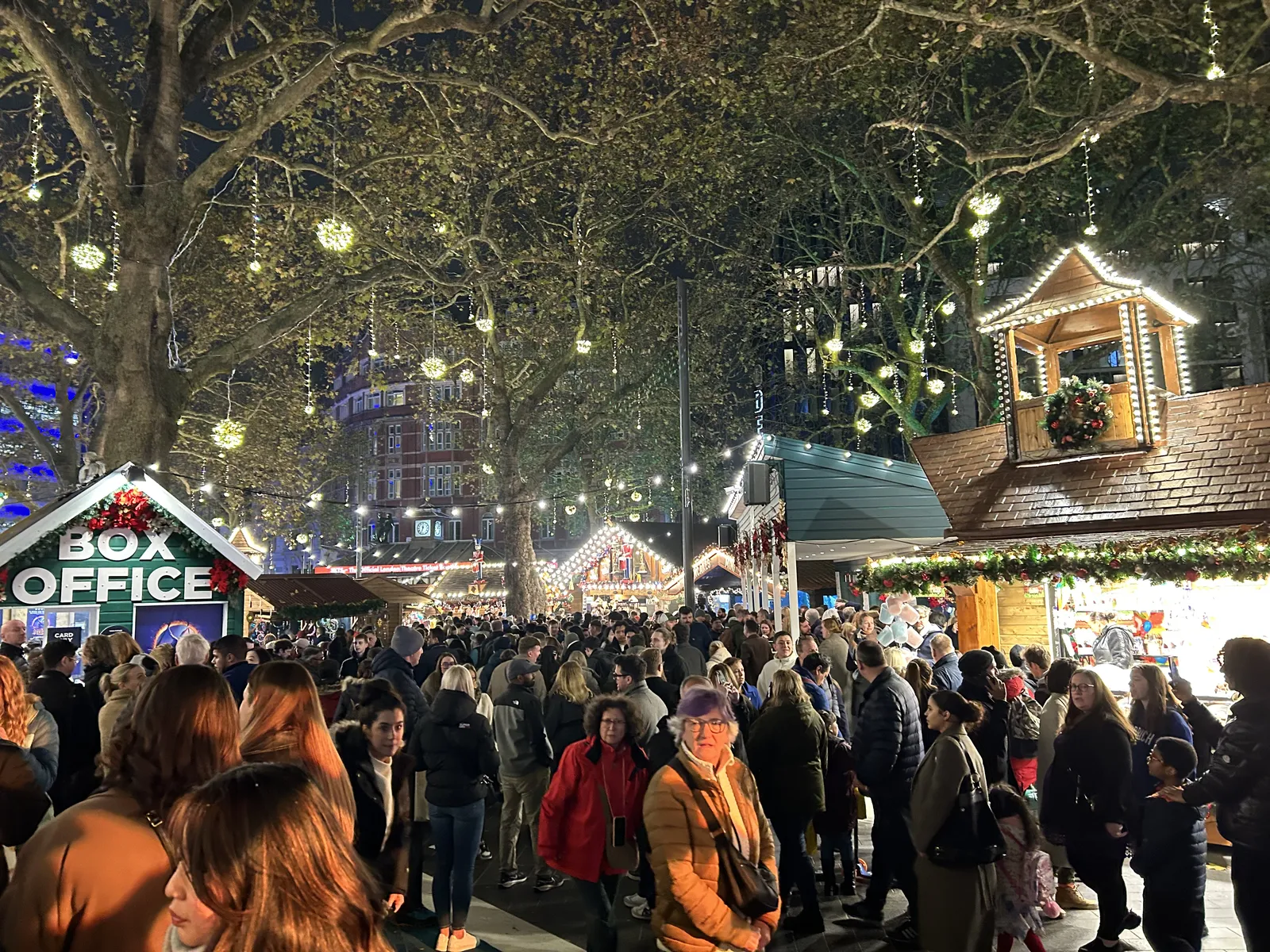 Crowds at a London Christmas market under trees strung with lights