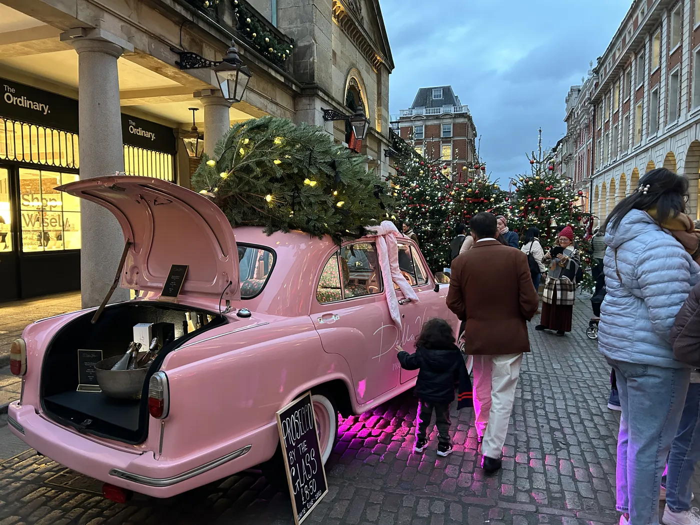 Pink vintage car with a Christmas tree on the roof in Covent Garden