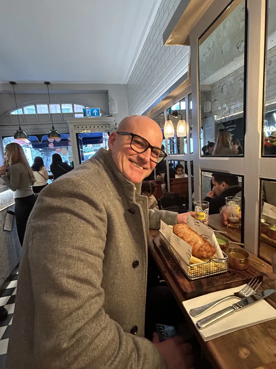 Jason smiling at lunch in a London restaurant