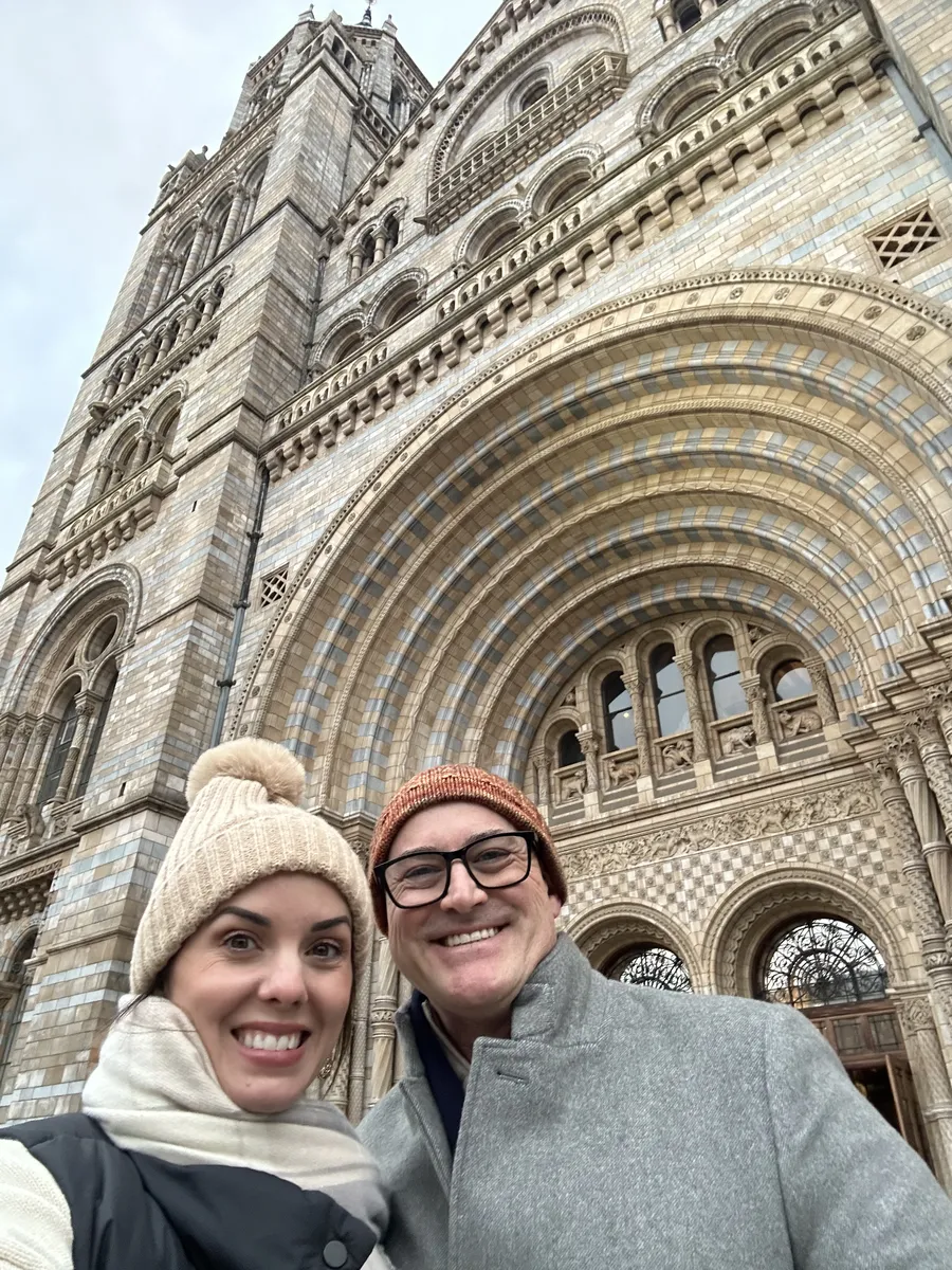 Jason and Heather in winter hats outside the Natural History Museum in London