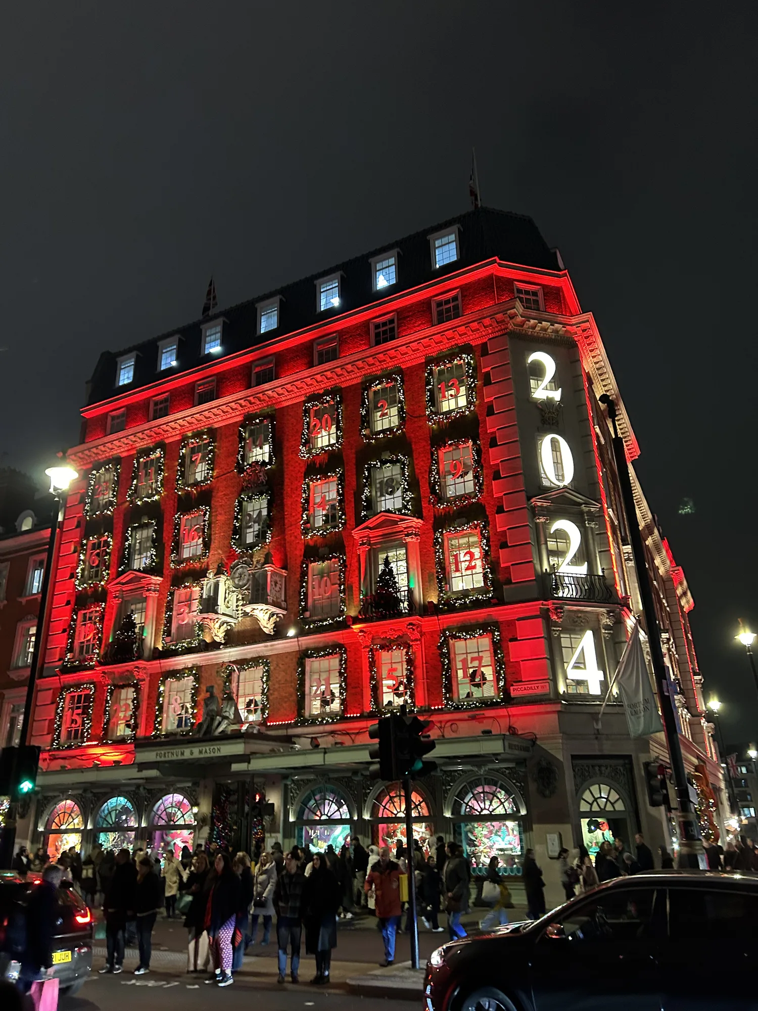A London department store lit up in red for the holidays with numbered windows like an advent calendar