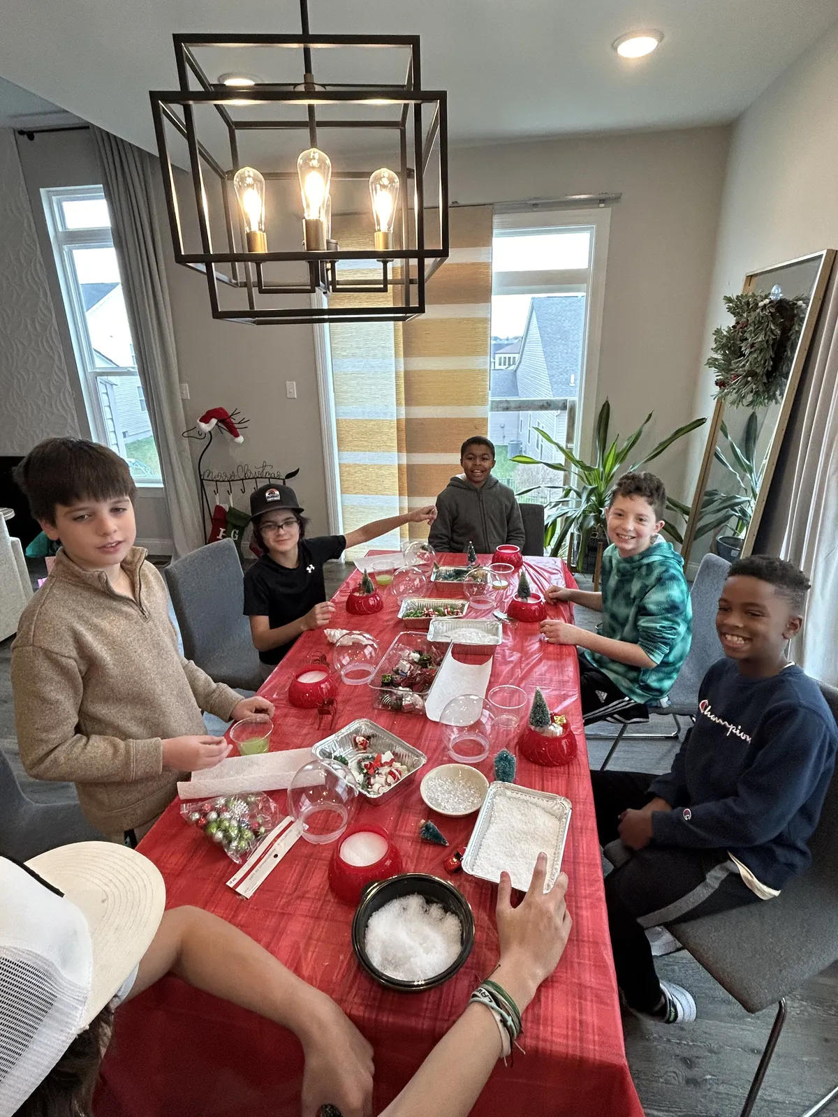 Kids around a long table covered in red, building their own snow globes