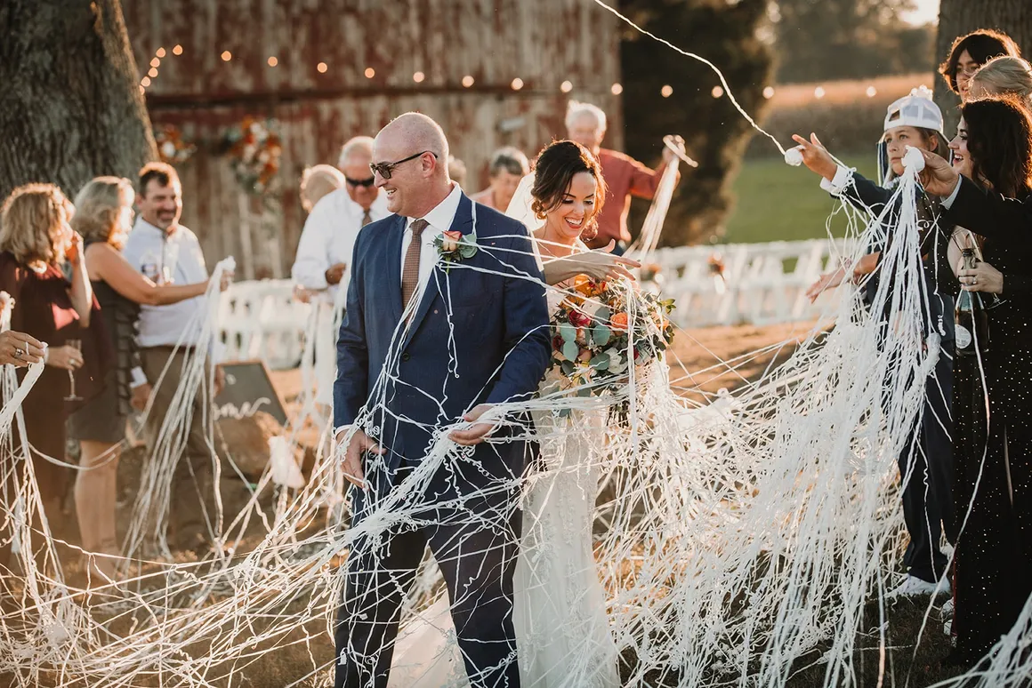 Jason and Heather walking through white streamers after the ceremony — pure joy